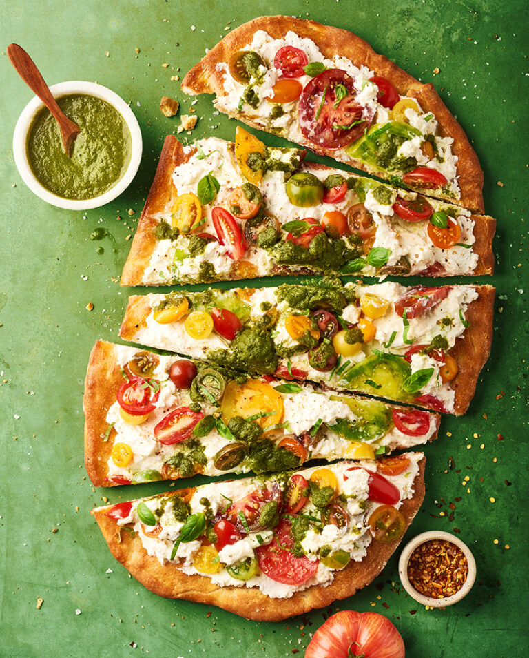 Overhead shot of a sliced flatbread on a green tabletop