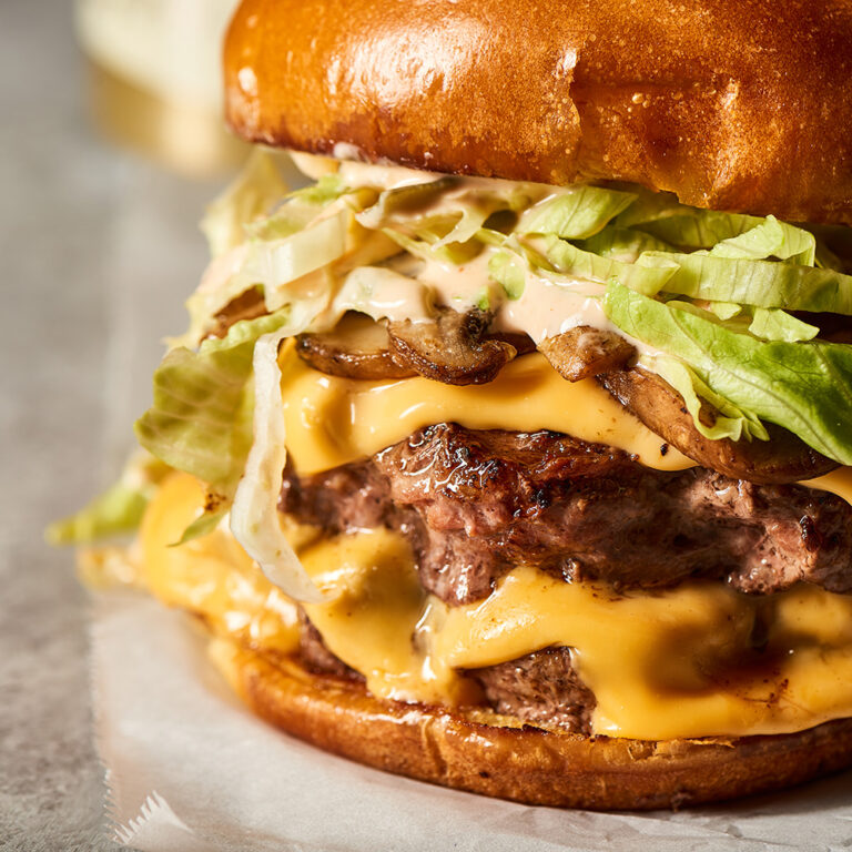 Close up of a burger with cheese, mushroom and lettuce